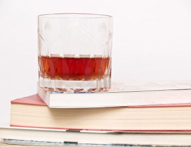 Glass of whiskey on books clipart