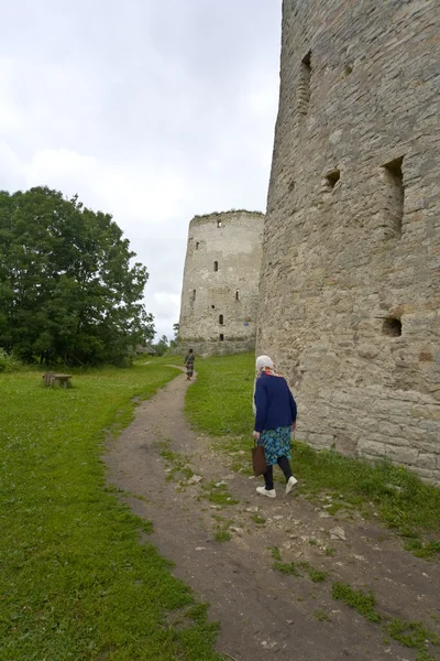 Old women passing by Izborsk ruins. — Stock Photo, Image