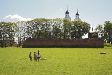 Three children on field by Livonia order castle ruins and church clipart