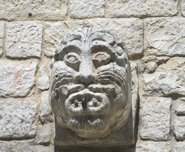 Ancien visage de pierre sculpté sur un mur de briques . — Photo