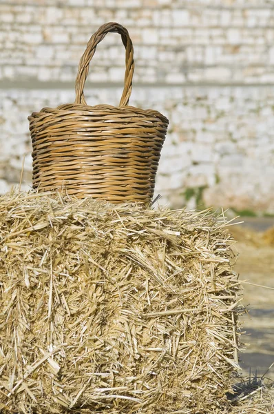 Wicker basket leaning on haystack bale. — Stock Photo, Image