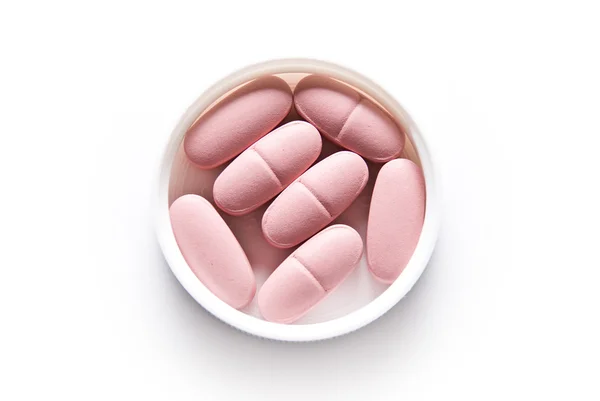 Розовые таблетки, лежащие в крышке — стоковое фото