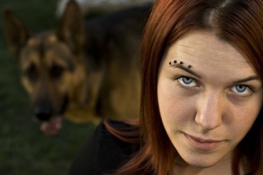 Girl looking at camera with her dog in the background clipart