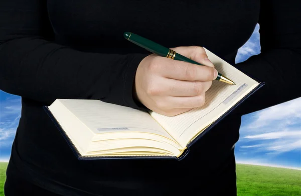 Kvinnlig hand skriver i en anteckningsbok — Stockfoto