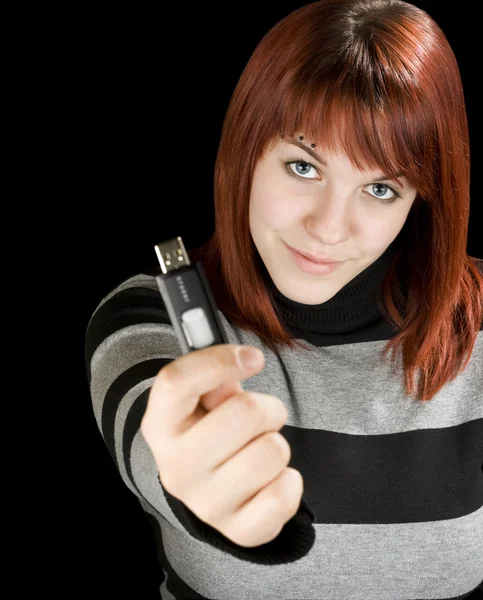 Redhead girl holding a flash drive at camera — Stock Photo, Image