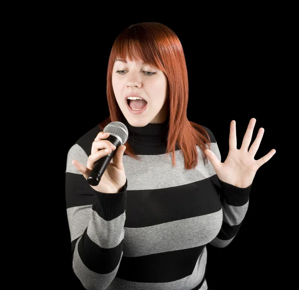 Ragazza rossa che canta karaoke sul microfono Foto Stock