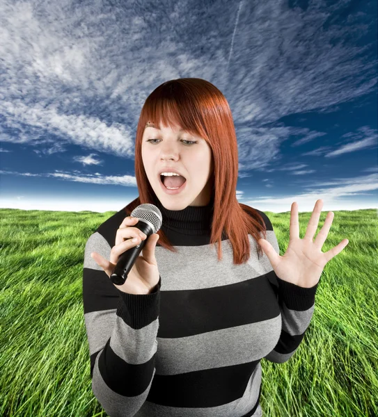 Redhead girl singing karaoke on microphone — Stock Photo, Image