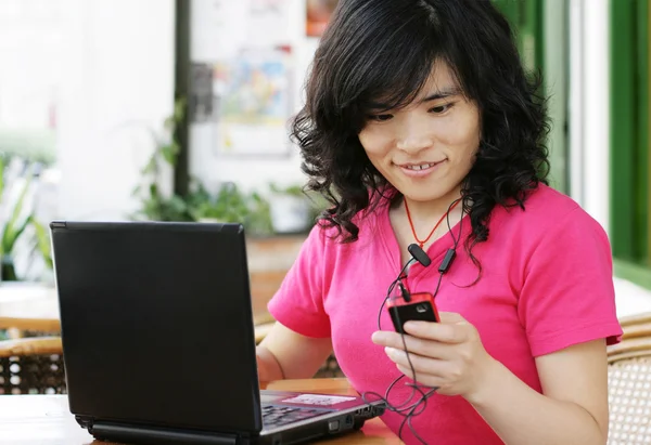 Woman using a laptop computer and cell p — Stock Photo, Image