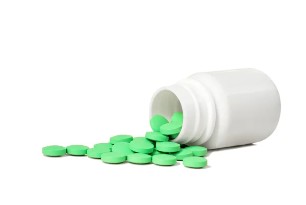 Green pills and a white container — Stock Photo, Image
