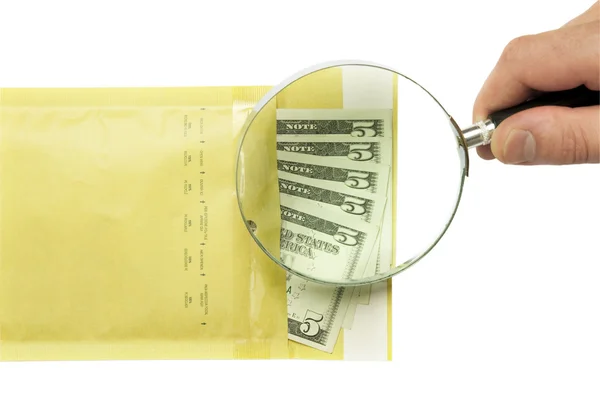 Dollars in the envelope and hand holding magnifying glass — Stock Photo, Image