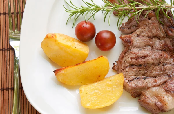 Biefstuk met aardappelen en cherry tomaten — Stockfoto