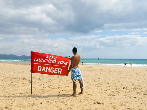 Jongen met een rode vlag in het strand — Stockfoto