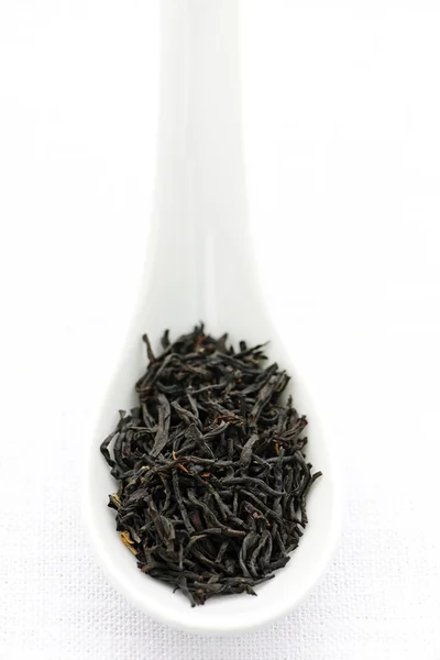 Suchý černý čaj listy v lžíci — Stock fotografie