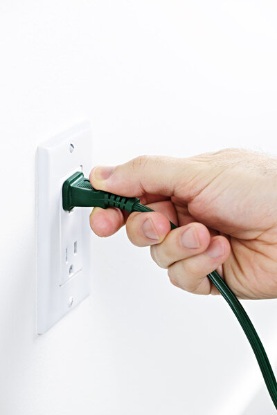 Hand removing plug from outlet