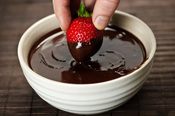 Hand dipping strawberry in chocolate — Stock Photo, Image