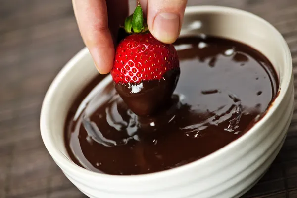 Mão mergulhando morango em chocolate — Fotografia de Stock
