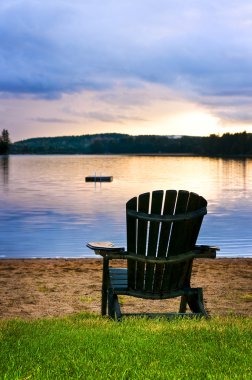 Wooden chair at sunset on beach clipart