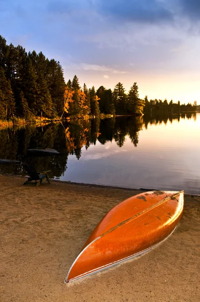 Sjön solnedgången med kanot på stranden — Stockfoto