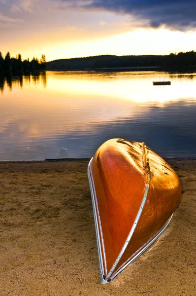Озеро захід сонця з каное на пляжі — стокове фото