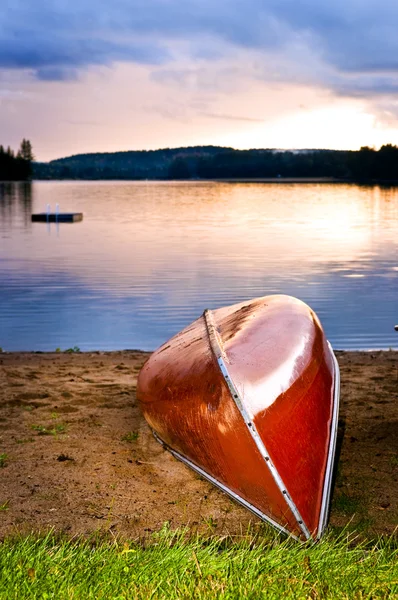 Sonnenuntergang am See mit Kanu am Strand — Stockfoto