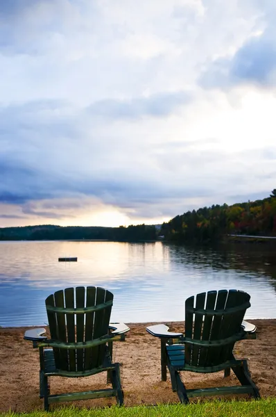 Houten stoelen bij zonsondergang op het strand — Stockfoto