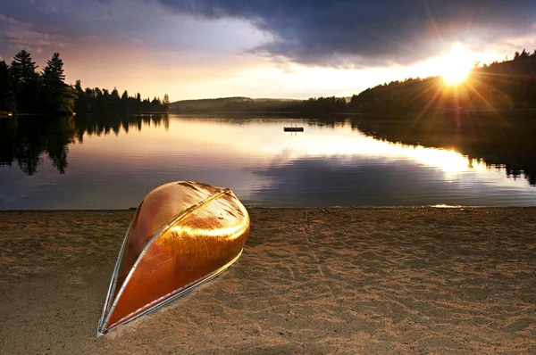 Jezero západ slunce s kánoí na pláži — Stock fotografie