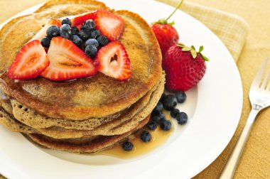 Stack of buckwheat pancakes with fresh berries and maple syrup clipart