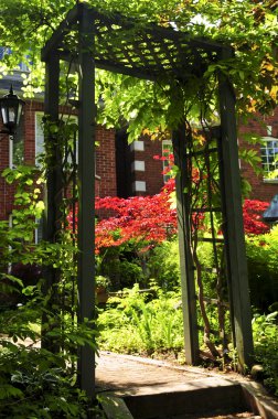 Landscaped front yard of a house with flowering garden and arbor clipart