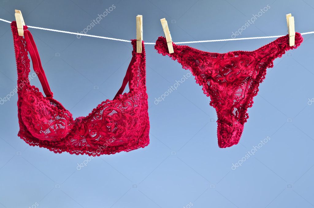 Woman hanging red and white bras on washing line Stock Photo