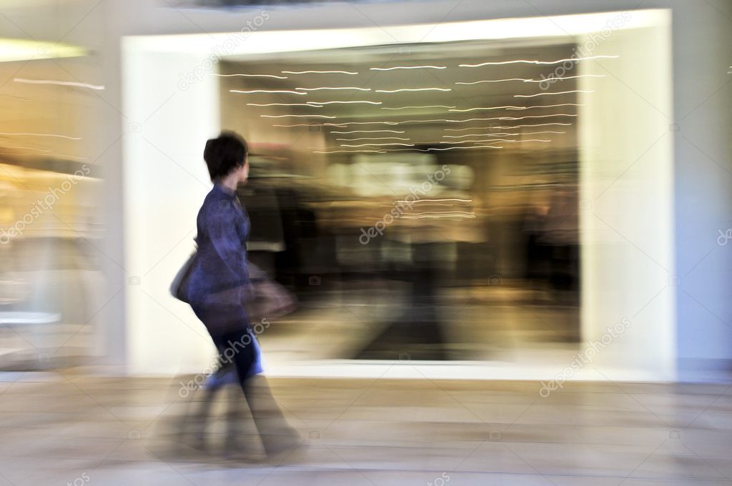 Woman shopping in a mall, panning shot, intentional in-camera motion blur