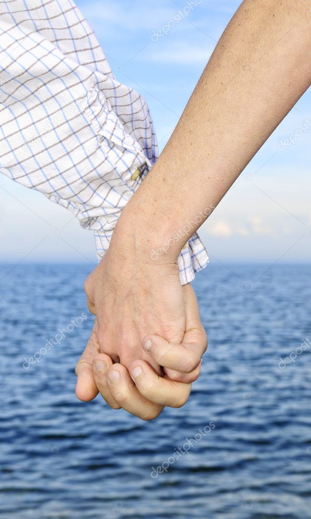 Mature romantic couple holding hands on the beach