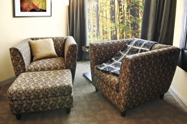 Comfortable armchairs with cushion and ottoman. Photo on the wall is my own. clipart