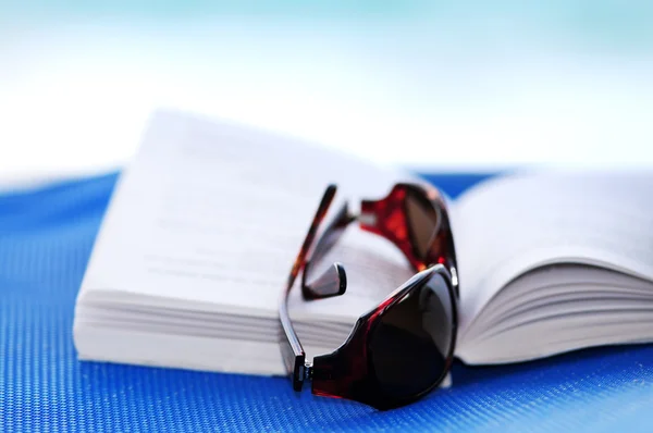 Solglasögon och bok på strandstol — Stockfoto
