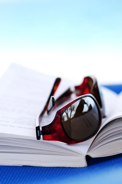 Güneş gözlüğü ve plaj sandalye üzerinde kitap — Stok fotoğraf
