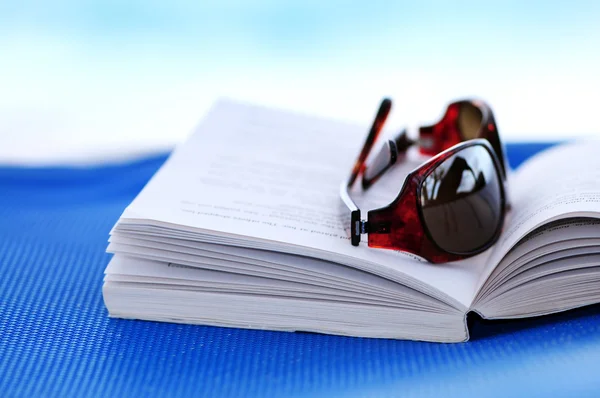 Óculos de sol e livro em cadeira de praia — Fotografia de Stock