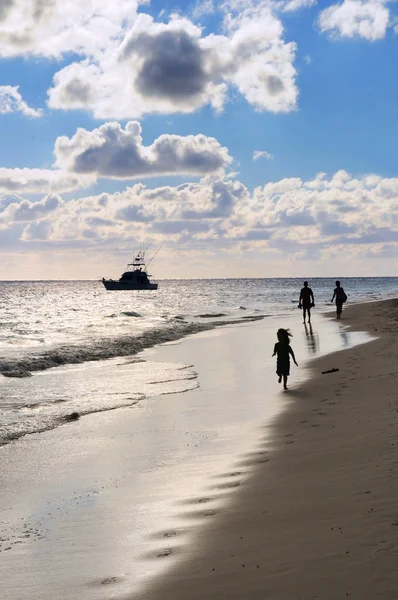 日没でトロピカル リゾートの砂浜での散歩の家族 — ストック写真