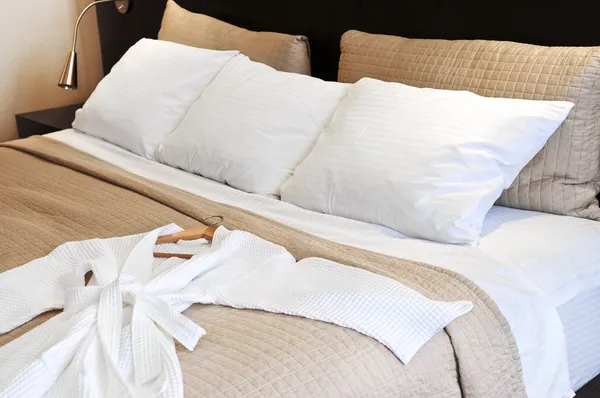 Кровать в отеле с халатом — стоковое фото