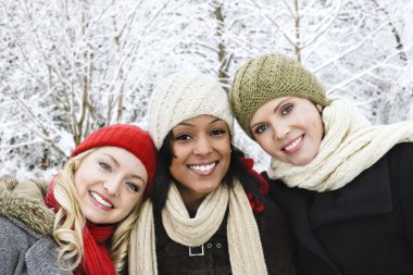 Group of three diverse young girl friends outdoors in winter clipart