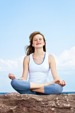 Genç kız dışarıda meditasyon yapıyor.