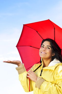 Beautiful young woman in raincoat with umbrella checking for rain clipart