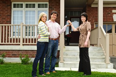 Happy couple getting keys to new house from real estate agent clipart