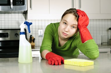 Tired girl doing kitchen cleaning chores with rubber gloves clipart