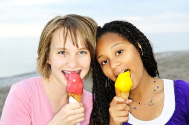 Portrait of two teenage girls eating ice cream cones clipart