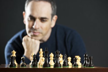 Satranç tahtasında satranç stratejisi düşünen bir adam.