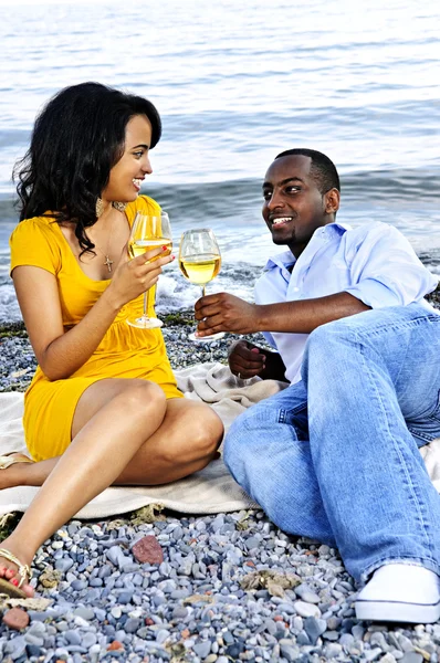 Счастливая пара пьет вино на пляже — стоковое фото