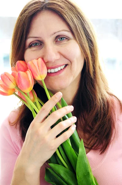 花の花束を保持している成熟した女性の笑みを浮かべてください — ストック写真