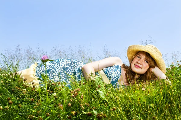 麦わら帽子で夏の草原の上に敷設若い 代の少女 — ストック写真
