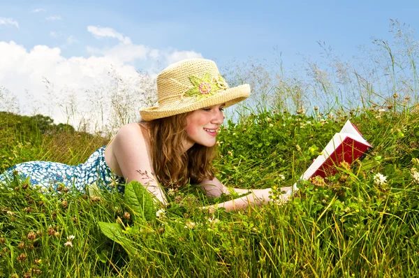 夏季草甸带草帽的年轻少女阅读书 — 图库照片