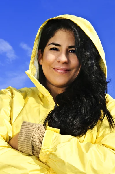青い空を背景に黄色いレインコートを着て美しい笑顔ブルネットの少女の肖像画 — ストック写真