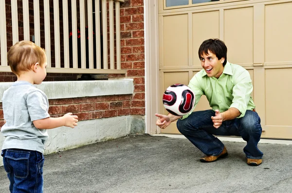 父亲教儿子在车道上踢足球 — 图库照片